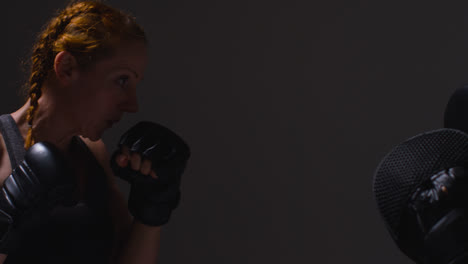 Close-Up-Studio-Shot-Of-Two-Mature-Women-Wearing-Gym-Fitness-Clothing-Exercising-Boxing-And-Sparring-Together-Shot-In-Profile